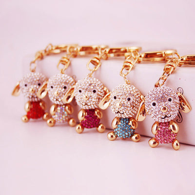 Five gold-tone dog keychains with rhinestone faces and different colored bodies.