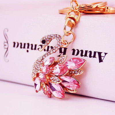Close-up of a pink faceted-stone swan charm on gold-tone keychain hardware.