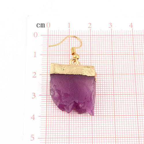 Purple gold-cap resin crystal earring on red grid centimeter scale