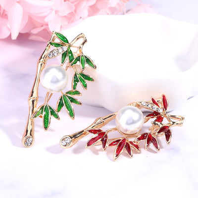 Front view of a slender green enamel leaf branch curled around a white pearl
