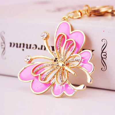 Close-up of a pink butterfly charm with gold-tone outlines and clear stone accents.