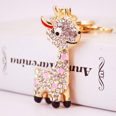 Close-up of a gold-tone giraffe charm with clear rhinestones and pink accents.
