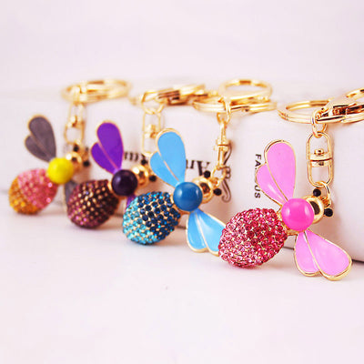 Four rhinestone bee keychains in pink, blue, purple and gray color combinations.