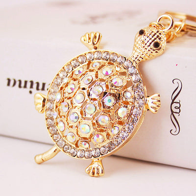 Close-up of a gold-tone turtle keychain covered with clear iridescent rhinestones.