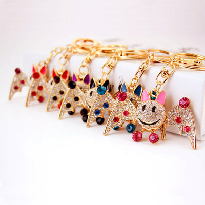Assorted gold-tone bat keychains lined up with pink, blue, red, black, and purple stones.
