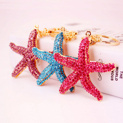 Three pink, blue, and purple rhinestone starfish keychains arranged together.