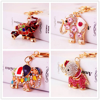 Four gold-tone elephant keychains display red, pink, multicolor, and rhinestone-covered designs.