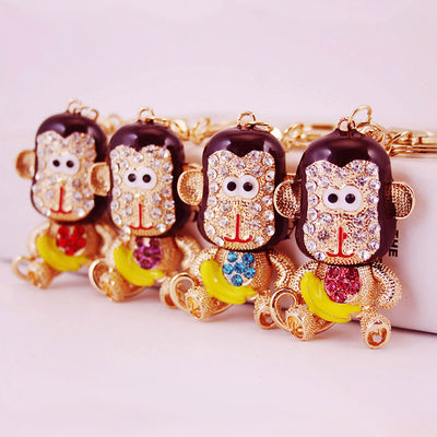 Four gold-tone monkey keychains display red, purple, blue, and pink chest rhinestones.