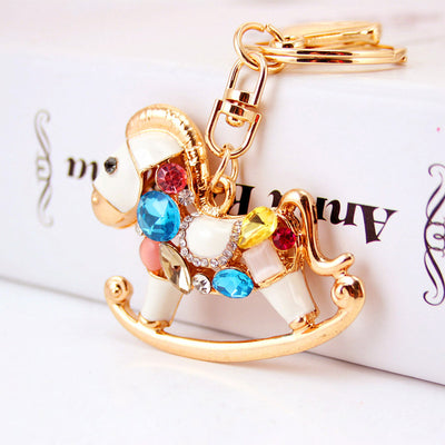 Front close-up of a gold-tone rocking horse keychain covered with multicolor faceted stones.