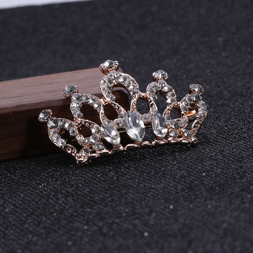 Rose gold crown brooch leaning on wood dark fabric