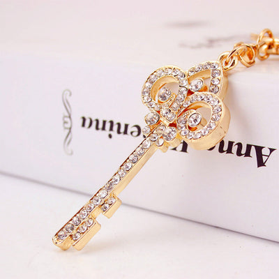 Close-up of a gold-tone decorative key charm covered with clear rhinestones.