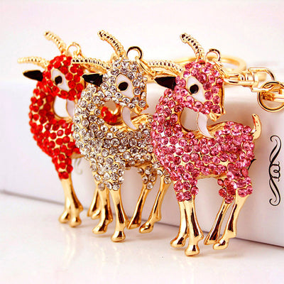 Three rhinestone goat keychains in red, clear, and pink stand side by side.