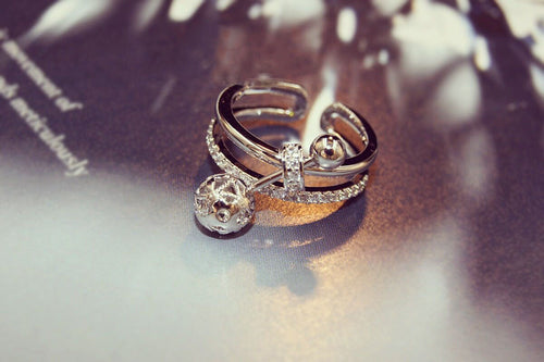 Side detail view of silver tone open ring with two clear dangle stones