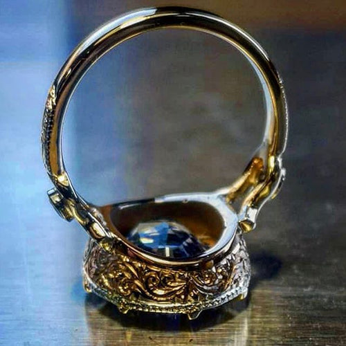 金色蓝紫椭圆石光环戒指 alternate angle showing an oval blue-purple center stone surrounded by a clear halo