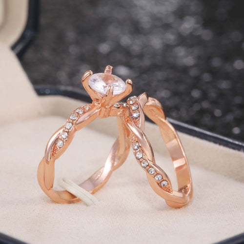 Side detail view of rose gold tone curved ring set with round clear stone