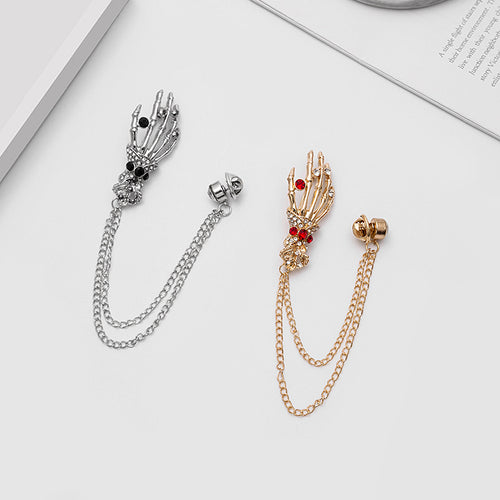 Gold and silver skeleton hand chain brooches on white desk