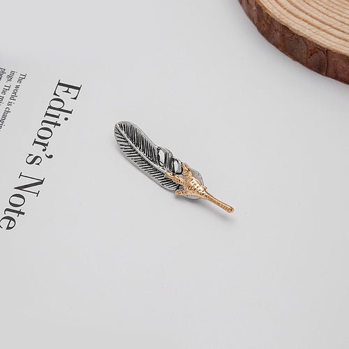Eagle claw feather brooch on paper beside wood slice