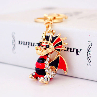 Close-up front view of a gold-tone dragon keychain with red, black, and clear details.