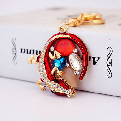 Close-up of the red lizard charm showing clear, blue, red, and pale decorative accents.