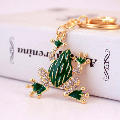 Green frog charm with raised feet, clear rhinestones, and a split key ring on a printed box