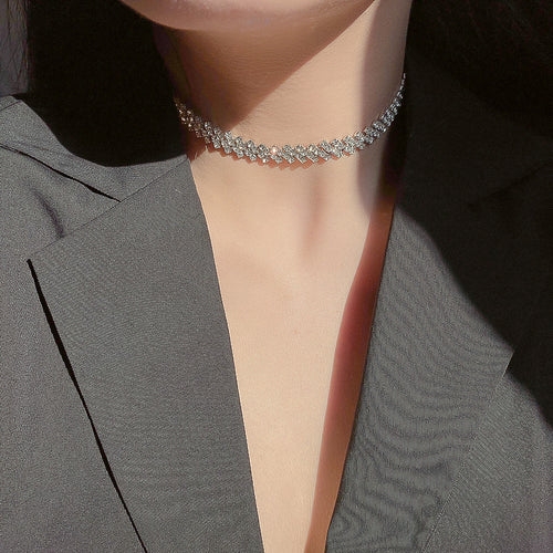 Silver clear zigzag rhinestone choker worn on neck with gray blazer