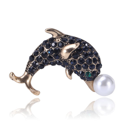 Front product view of the leaping dolphin covered in dark crystals and balancing a pearl-like ball brooch