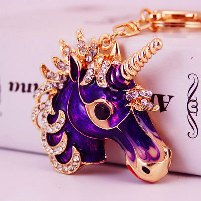 Close-up of a purple unicorn head with a gold-tone spiral horn and clear rhinestone mane.