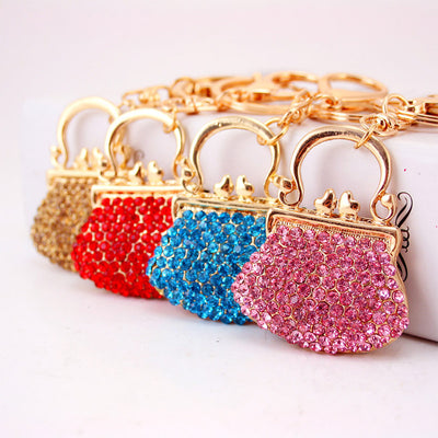 Four purse-shaped rhinestone keychains in brown, red, blue, and pink.
