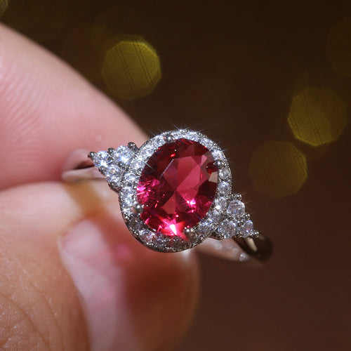 Product view showing silver-tone red oval halo three-stone ring