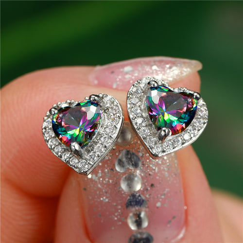Iridescent heart halo stud earrings held on a fingertip