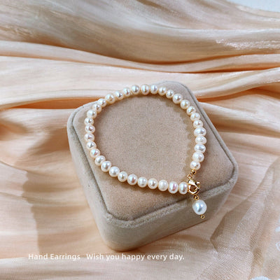 White pearl-like strand bracelet with single drop in the first product display.