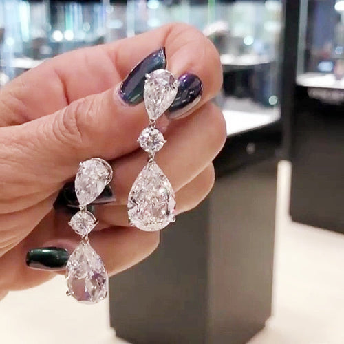 Second product view showing silver-tone pear and round clear three-stone long drop earrings
