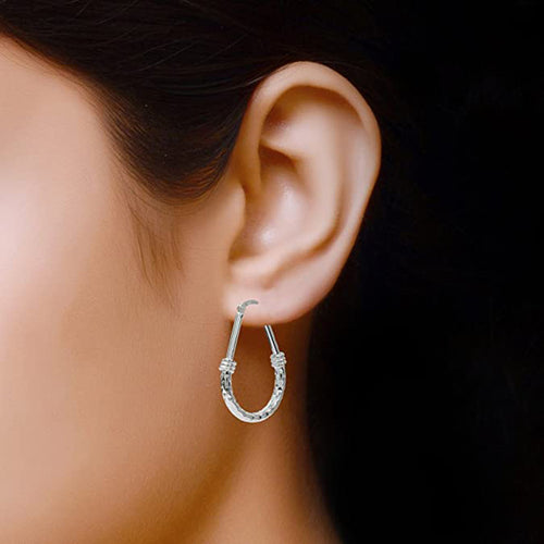 Silver teardrop hoop earring worn on ear close-up
