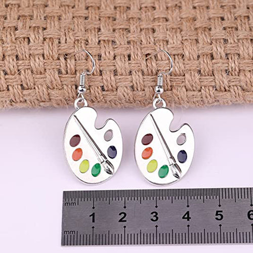 Silver palette earrings on burlap with metal ruler below for scale