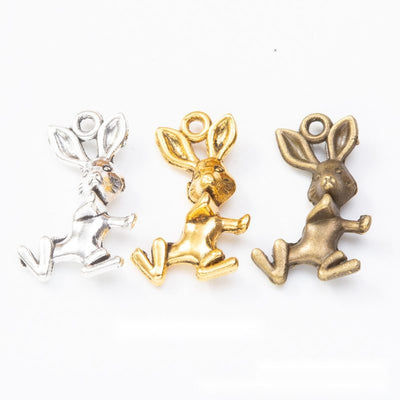 Grouped front views of the running rabbit metal charm in three metallic finishes