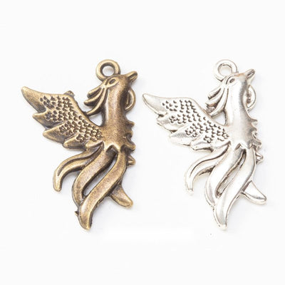 Phoenix Bird Charm Pendant finish comparison showing spread wings, a crested head, and flowing tail feathers