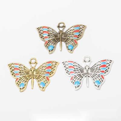 Product view of enamel butterfly pendant showing a large openwork butterfly with red and blue enamel accents and a top b