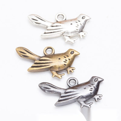 Assorted flying bird charms arranged together on a white background