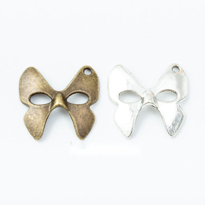 Grouped front views of the bow masquerade mask metal charm in two antique finishes