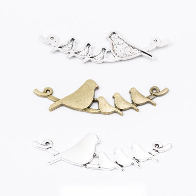 Grouped front views of the birds on branch double loop connector in two antique finishes