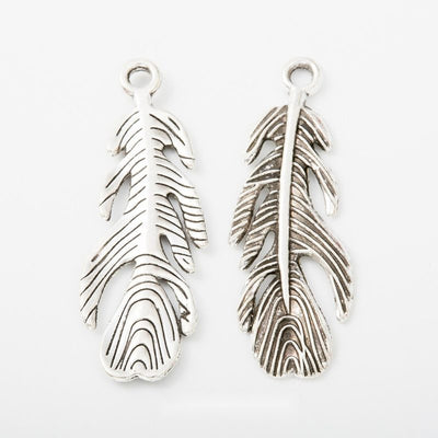 detailed long feather metal charm in antique silver finish shown together in the available finishes
