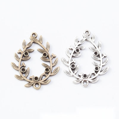 Ornate teardrop connectors with raised leaf scrollwork arranged together on a white background.