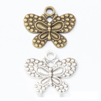 dotted butterfly metal charms in two antique finishes shown together in the available finishes
