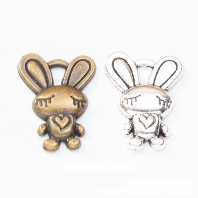 Grouped front view of heart holding bunny charms in the available finishes