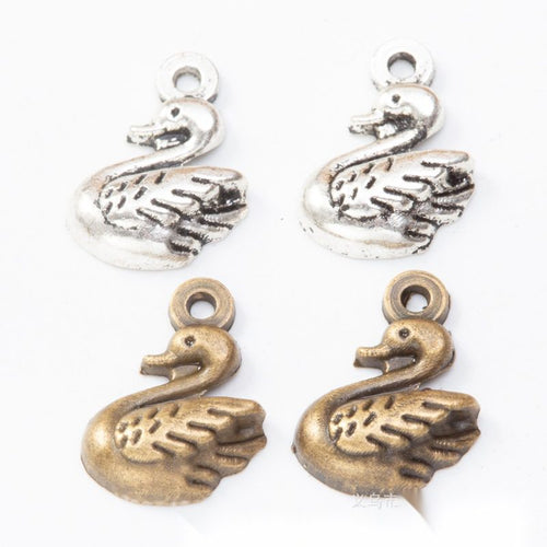 Grouped front views of the small swan pendant charm in two antique metal finishes