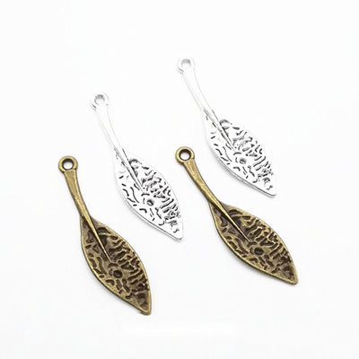filigree long leaf metal charms in two antique finishes shown together in the available finishes
