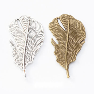 Assorted textured feather charms arranged together on a white background