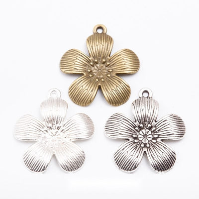Assorted five petal flower charms arranged together on a white background