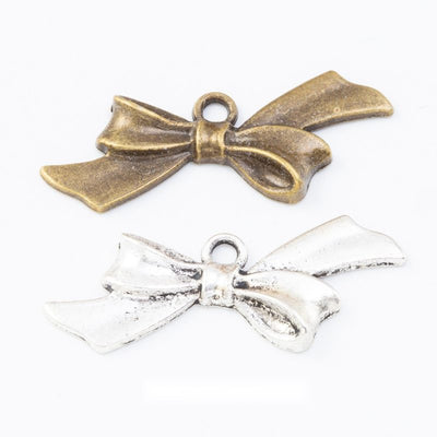Wide tied bow charms with folded ribbon tails and a center loop arranged together on a white background.
