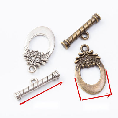 Oval toggle rings with raised floral scrollwork and matching bars arranged together on a white background.